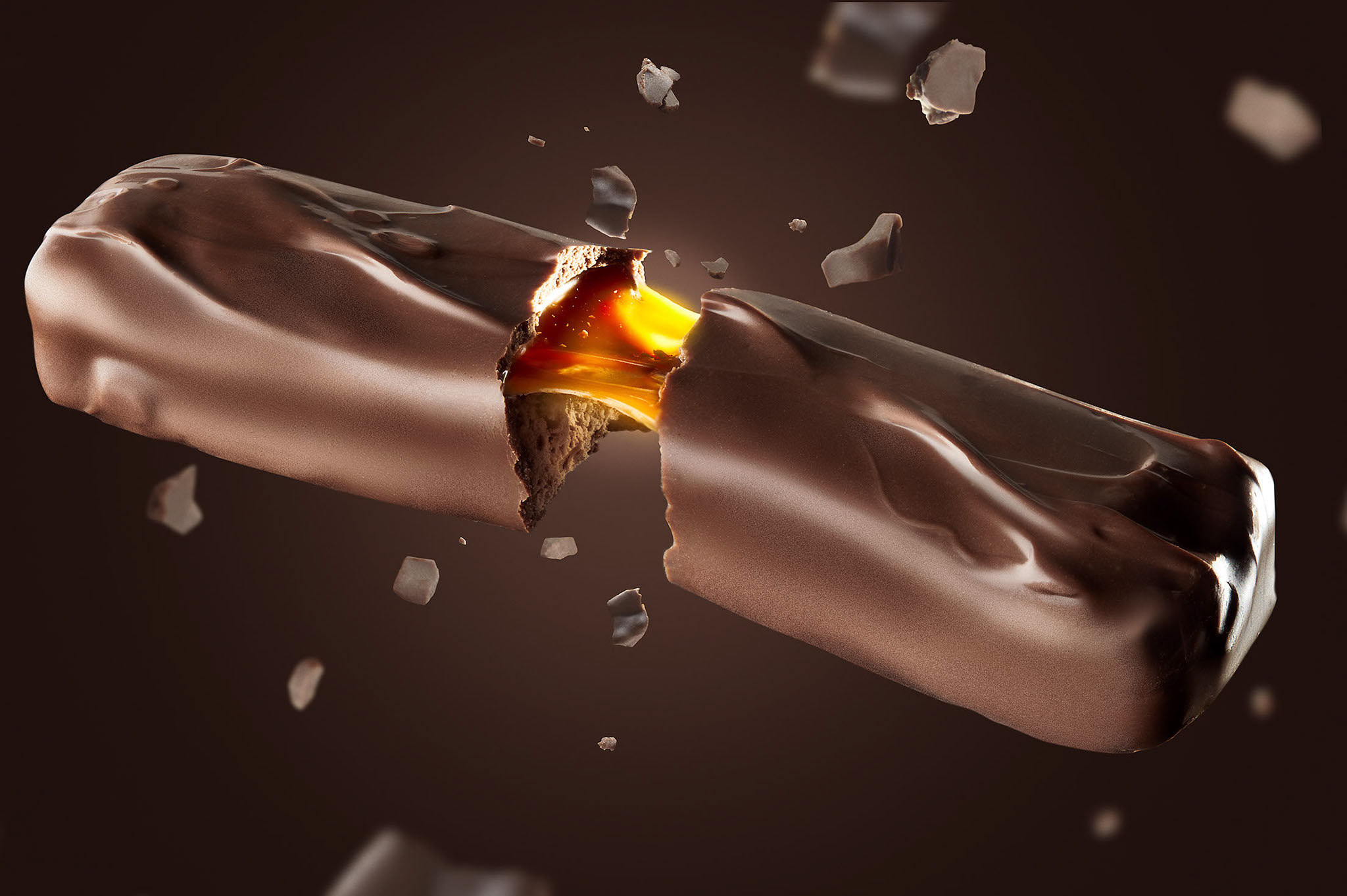 Mars bar exploding open on a dark background and caramel stretching between the pieces