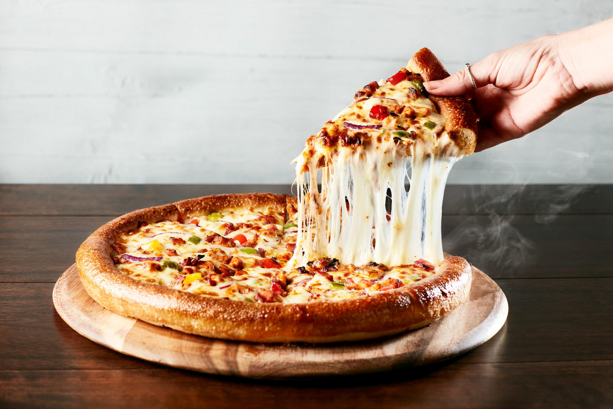 Freshly baked pizza with gooey melted cheese being served.