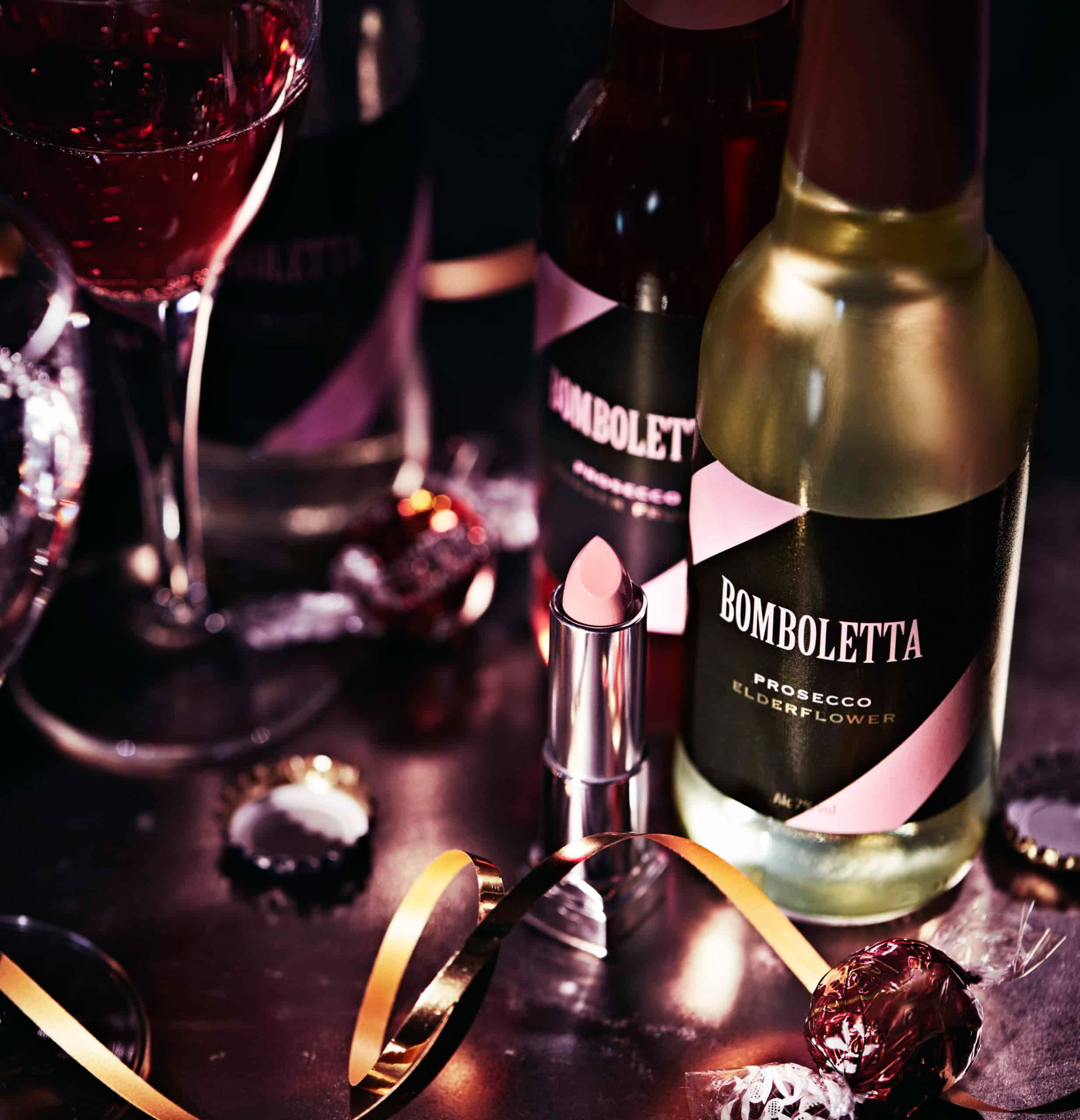 Bottles of flavoured prosecco on a table with makeup, streamers and glasses