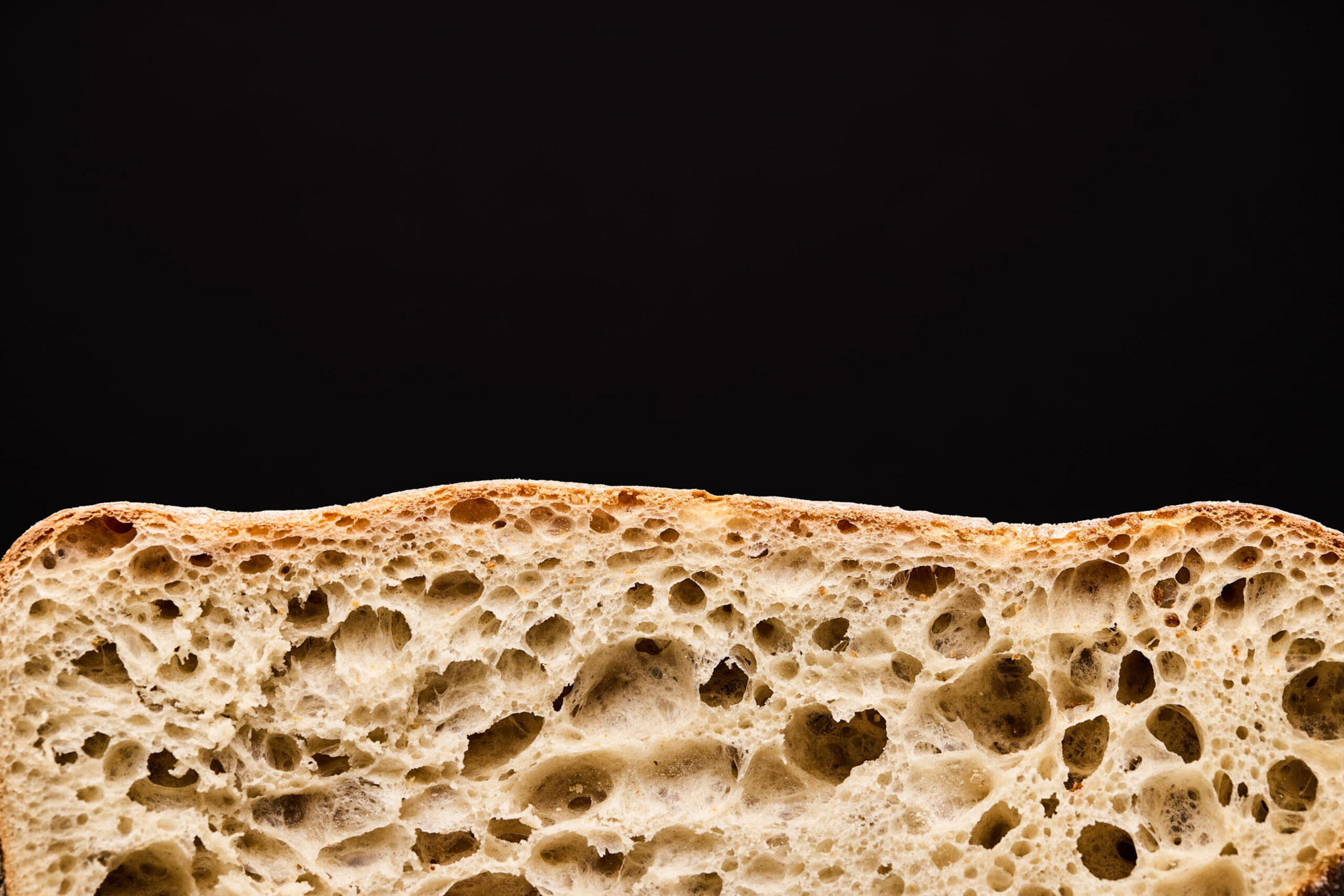 Rye bread slice on a black background showing all the open texture of the bread