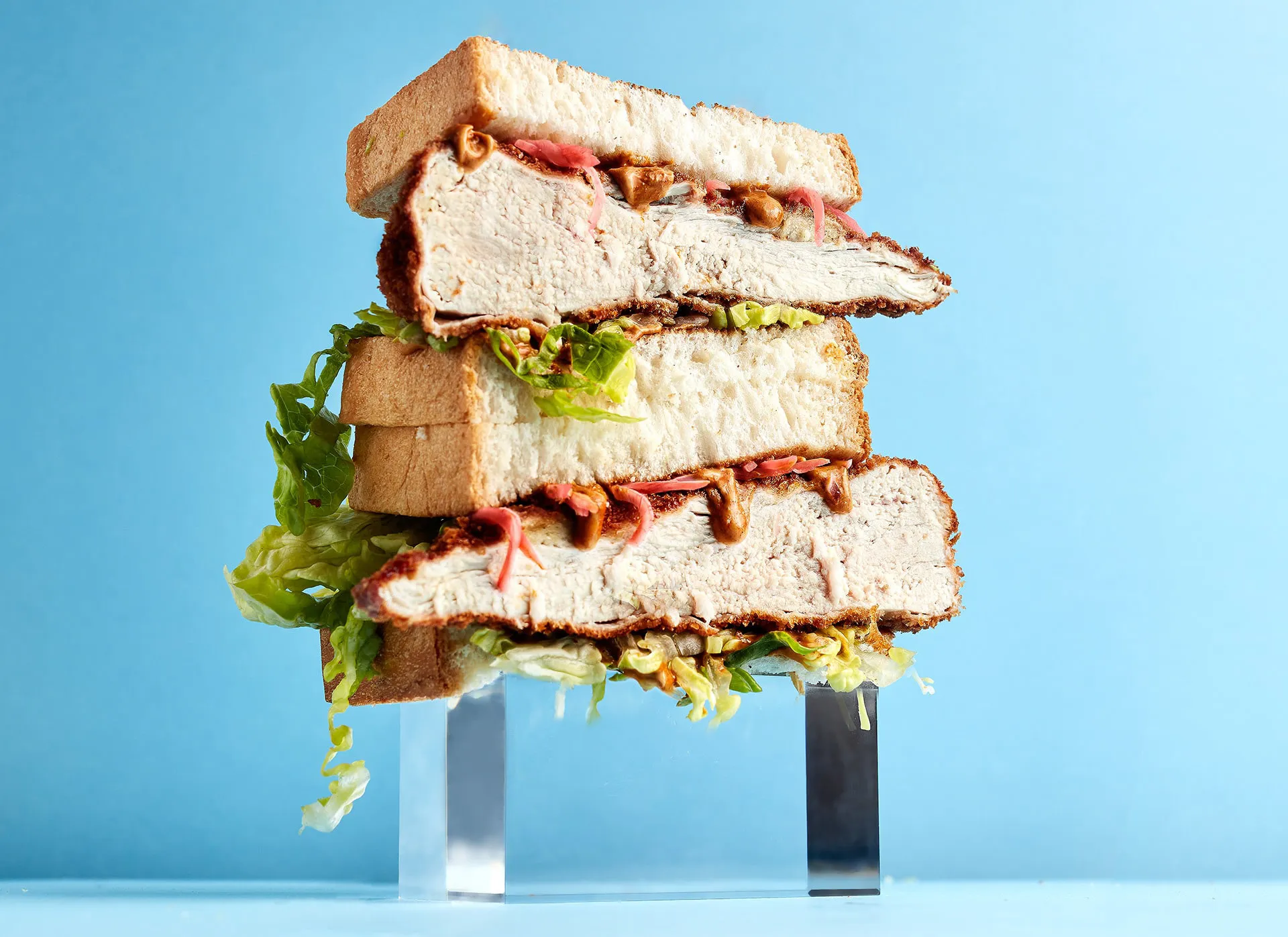 Mouthwatering towering chicken sandwich on blue background.