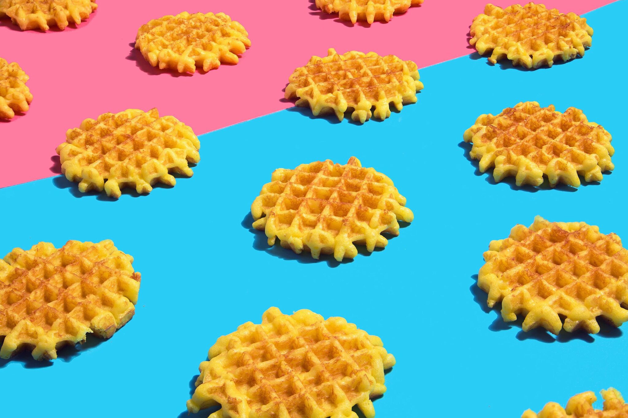 Waffles carefully laid out on blue and pink backgrounds with hard shadows