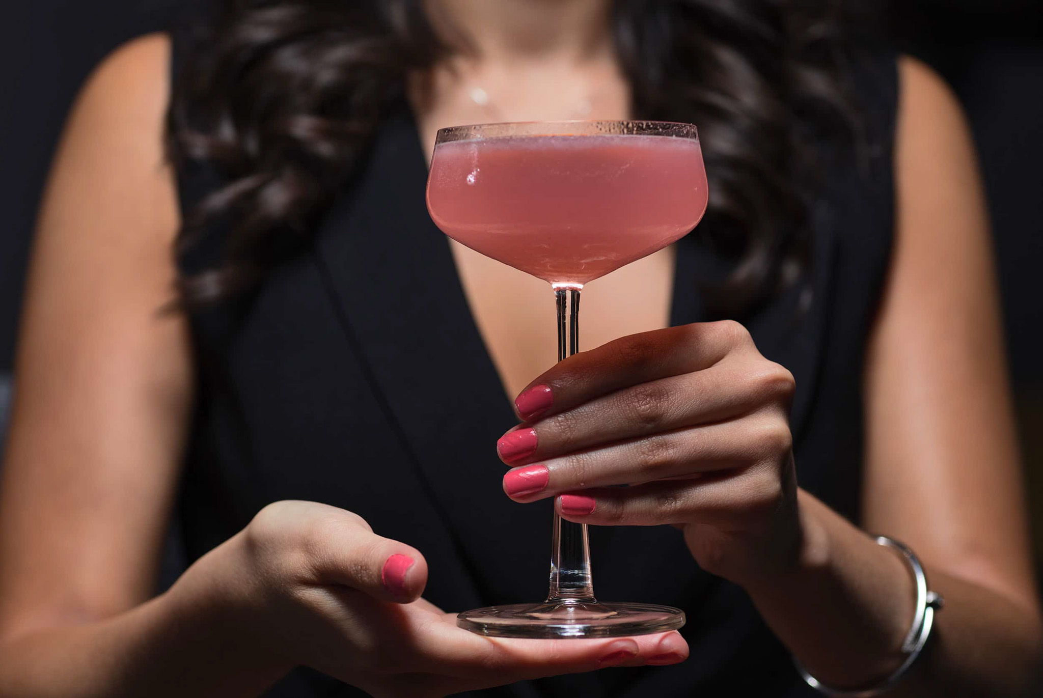 Pink cocktail being held by a woman