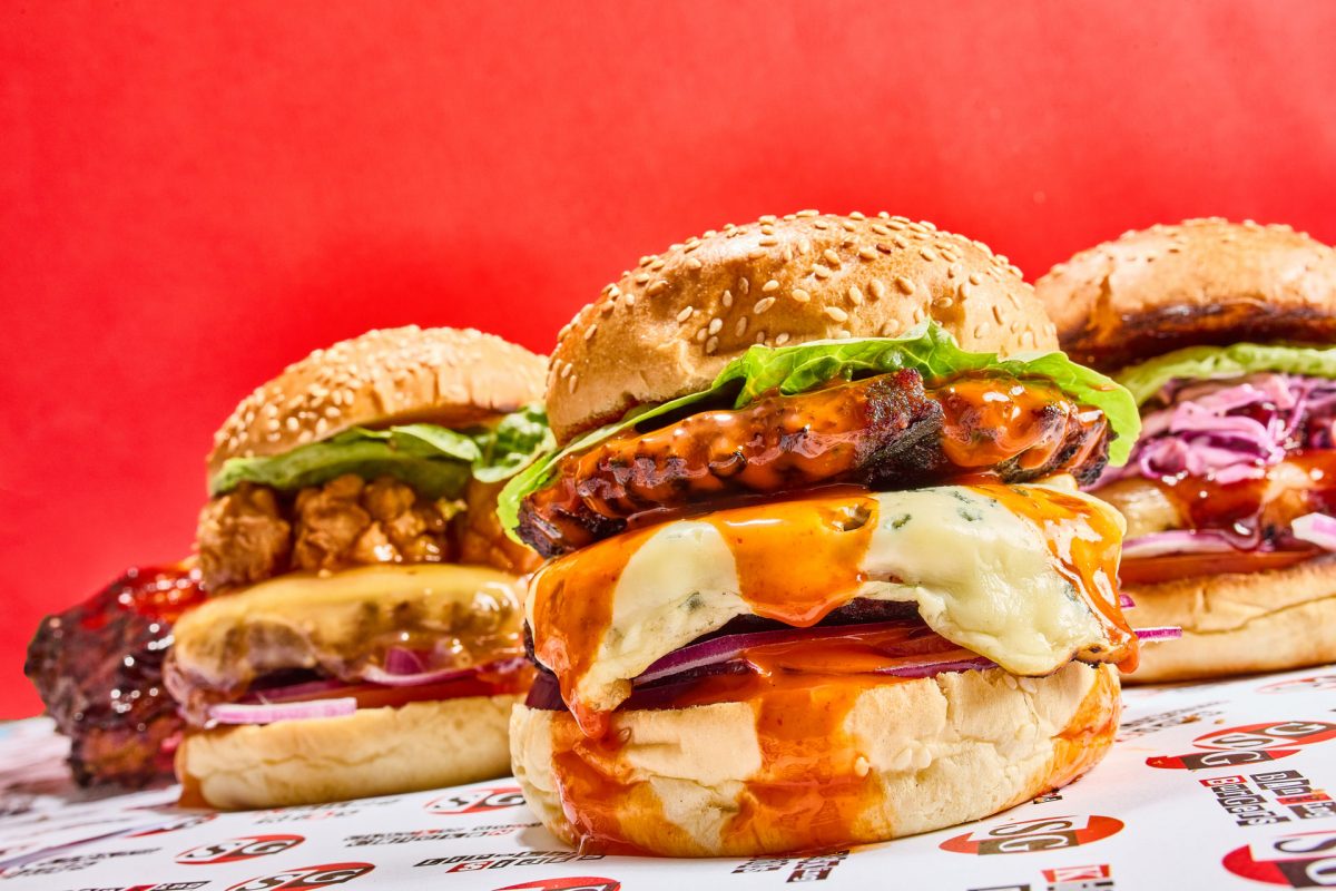 Three huge juicy cheese burgers on a red background at a slight angle