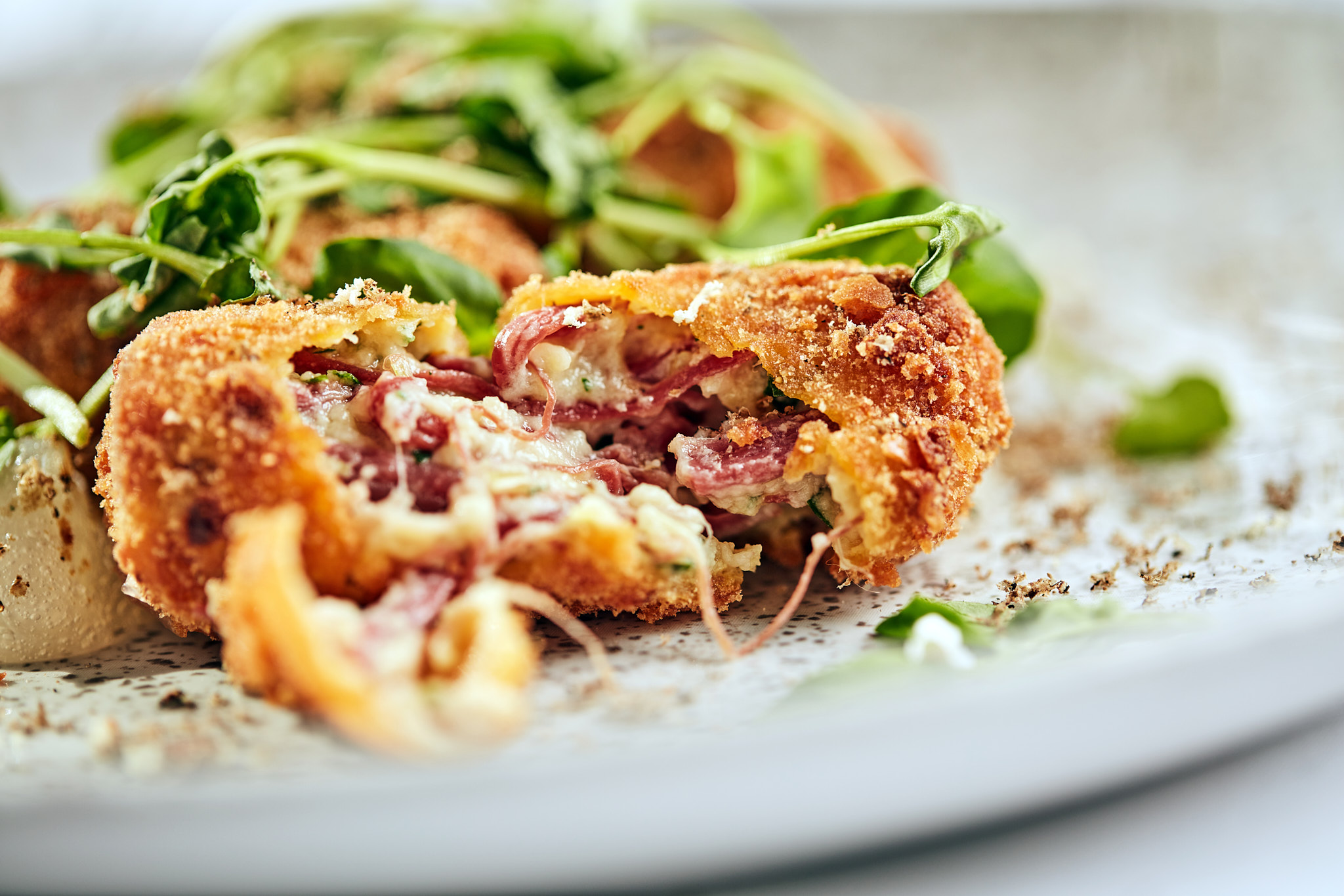 Ham and cheese croquettes with fresh garnish.