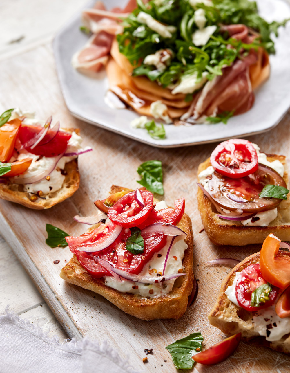 Fresh bruschetta with tomato, basil, and cheese on wooden board for appetizers.