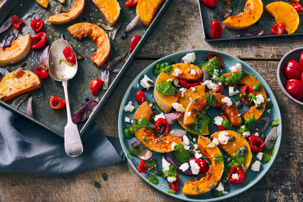 Delicious roasted pumpkin salad with cheese, herbs, and chili on rustic plate.