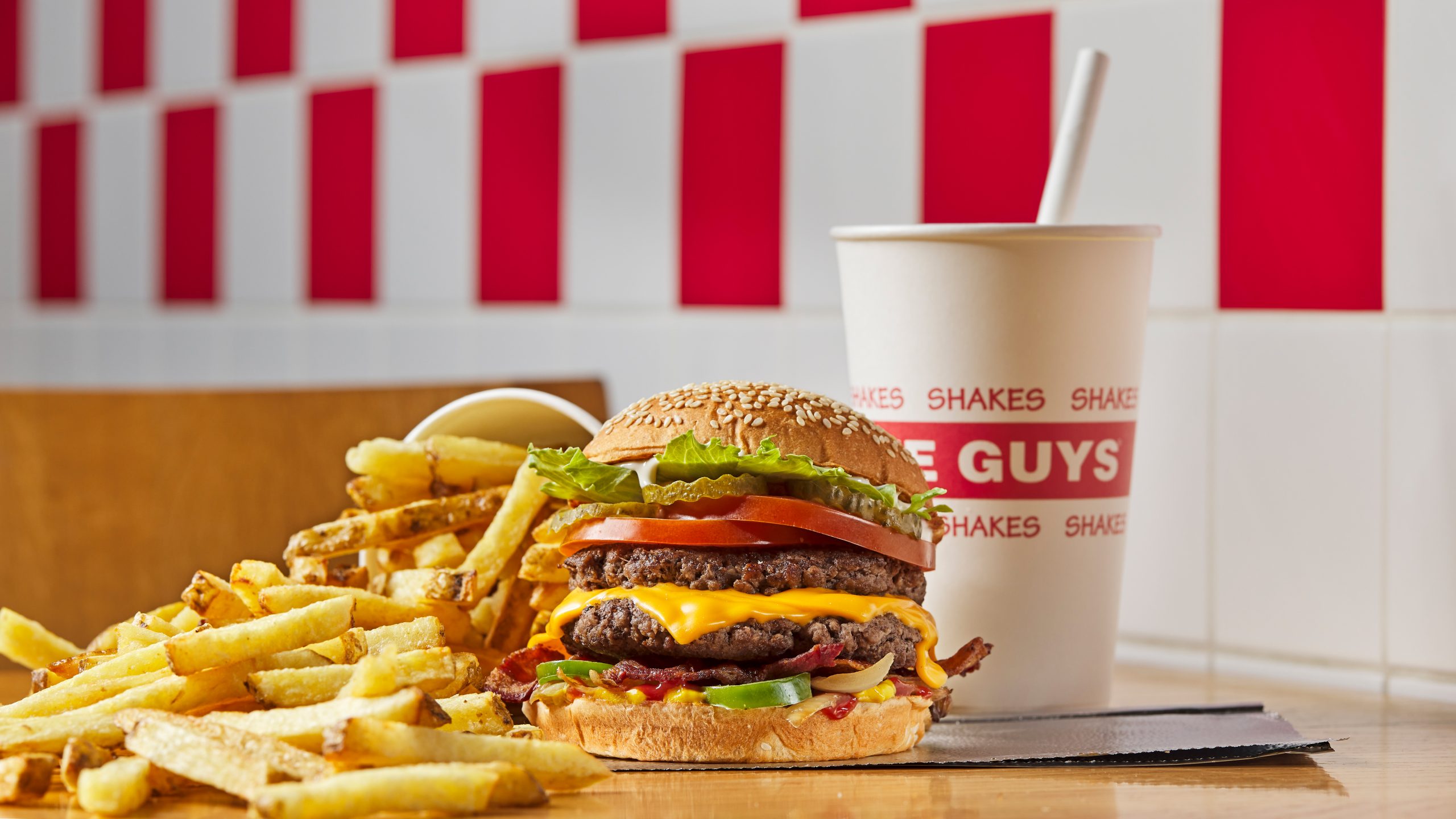 Juicy cheeseburger and crispy fries with milkshake, set against retro diner backdrop.